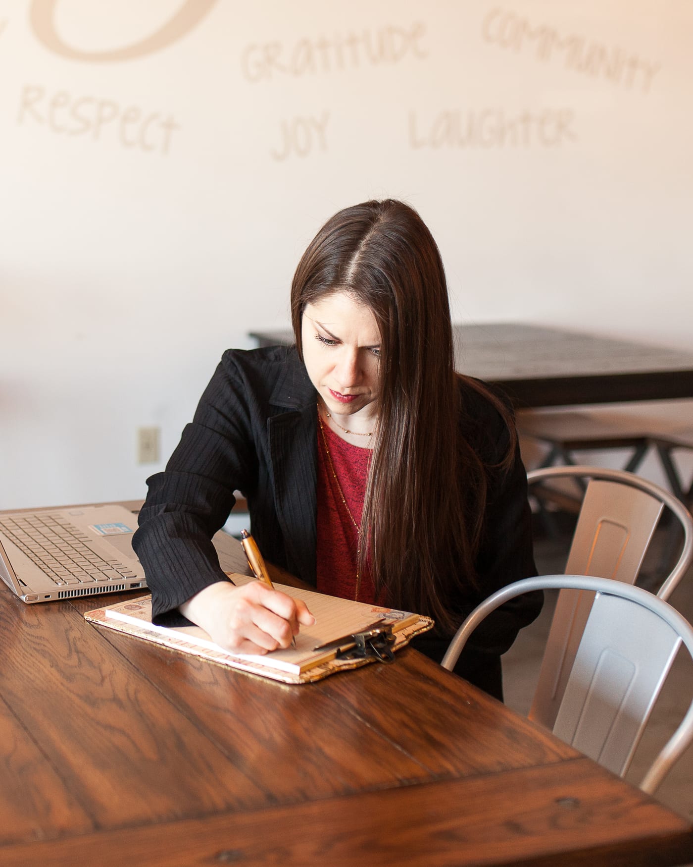 Jennifer Widmer working at a laptop and taking notes in a community space